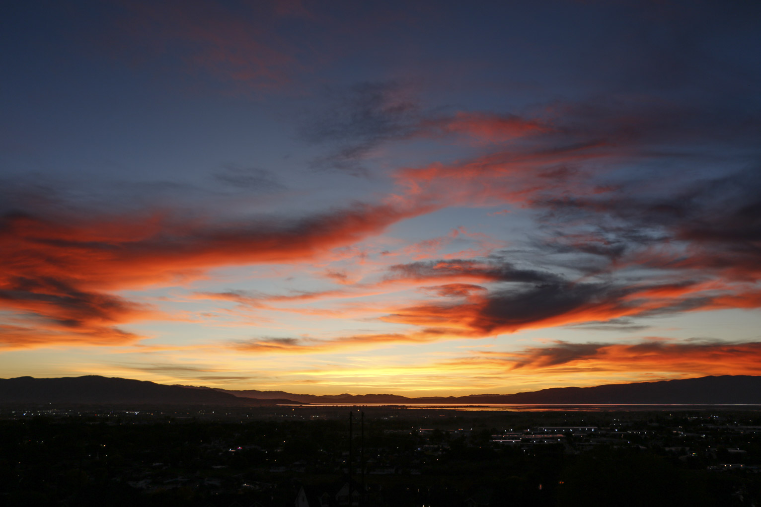 wavy clouds lit bright red by sunset over a town